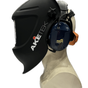 Ett mannekänghuvud bär Svetshjälms AKETEK® AUDIO hjälm avsedd för användning med hörselkåpor, visad i profil med svart ansiktsskydd och påsatt mörkblå Hellberg hörselkåpa mot en vit bakgrund.